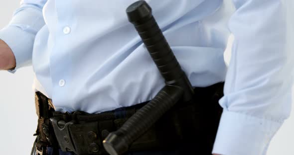 Mid section of security guard holding baton and walkie talkie alt