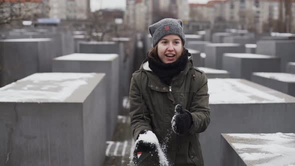 Young woman picking up handful of snow and throwing it in air, slow motion alt