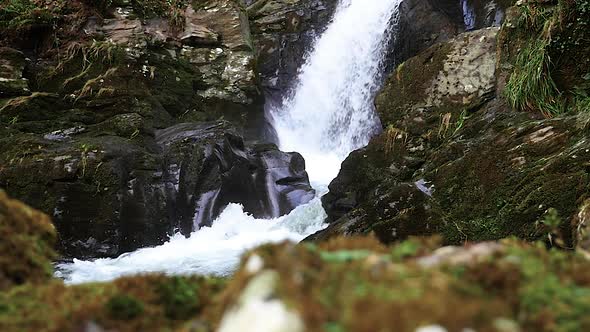 Low Angle View Of Waterfall Cascading Down Rocks In Slow Motion. Slow Slide Left alt