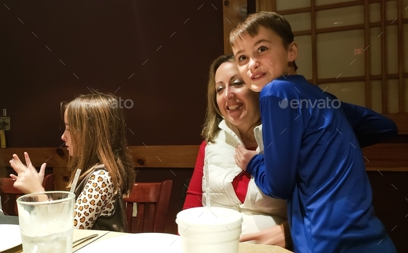 Millennial mom having fun in restaurant with generation z kids in funniest photos.
