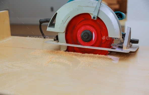 Carpenter cutting a kitchen cabinet with the disk saw during house renovation, carpentry tools