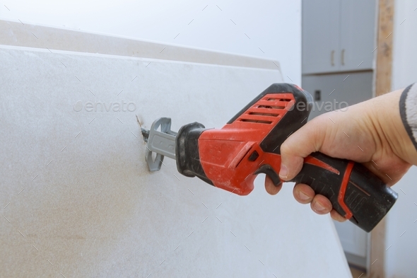 Worker cuts with a dirty saw drywall repair cutting gypsum board
