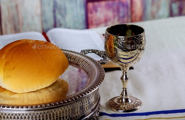 Taking Communion. Cup of glass with red wine, bread and Holy Bible on table close-up on bread