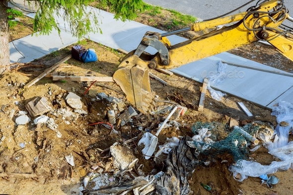 Backhoe working on garbage dump in soil pollution construction site
