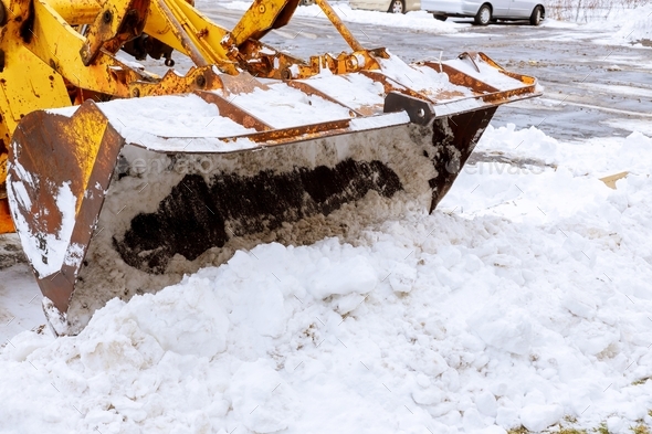 Closeup of excavator for snow removal on a snowy parking lot after blizzard