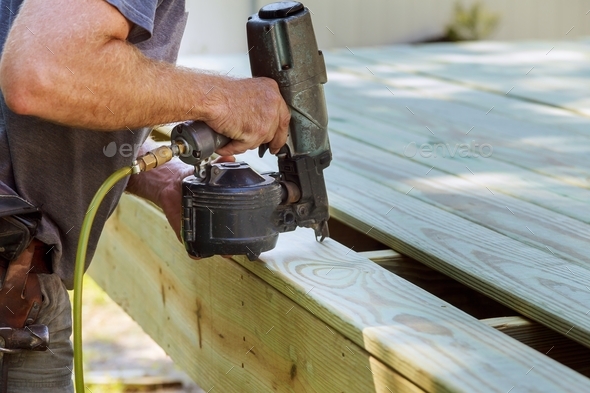 Installing Wood on deck, patio construction man using pneumatic nailer ...