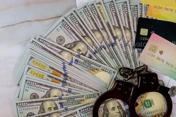 Handcuffs, US dollar banknotes cash credit cards on of cyber crime online fraud arrest pickpocket