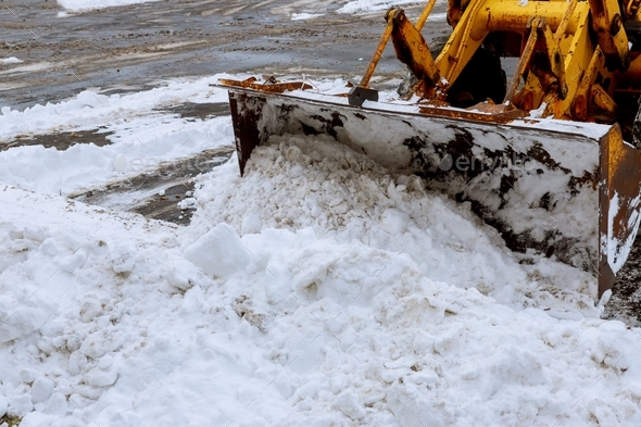 Closeup grader cleaning snow covered road after blizzard excavator for snow removal on a snowy
