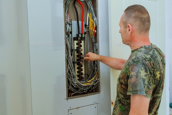 Professional electrician installing components in electrical shield The electrician checks the