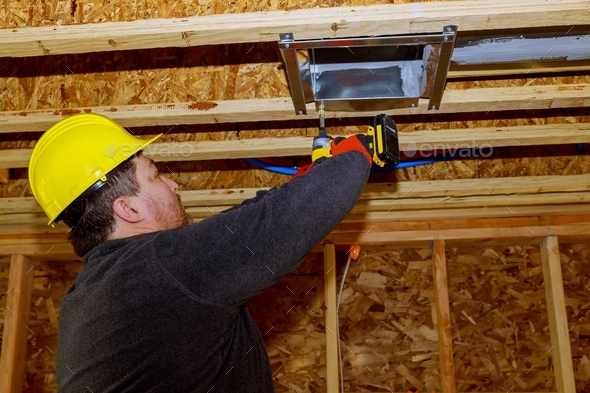 Worker installing new air conditioner vents in new home construction ...