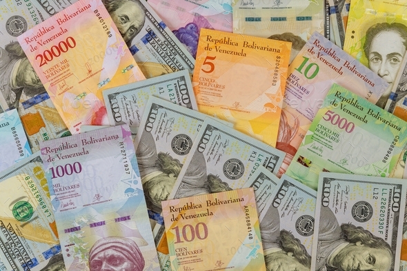 American dollar bills notes over Venezuelan Bolivar banknote with paper currency bills.