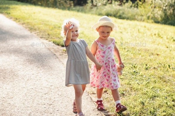 Two cute little girls walking in the park and holding hands Stock Photo ...