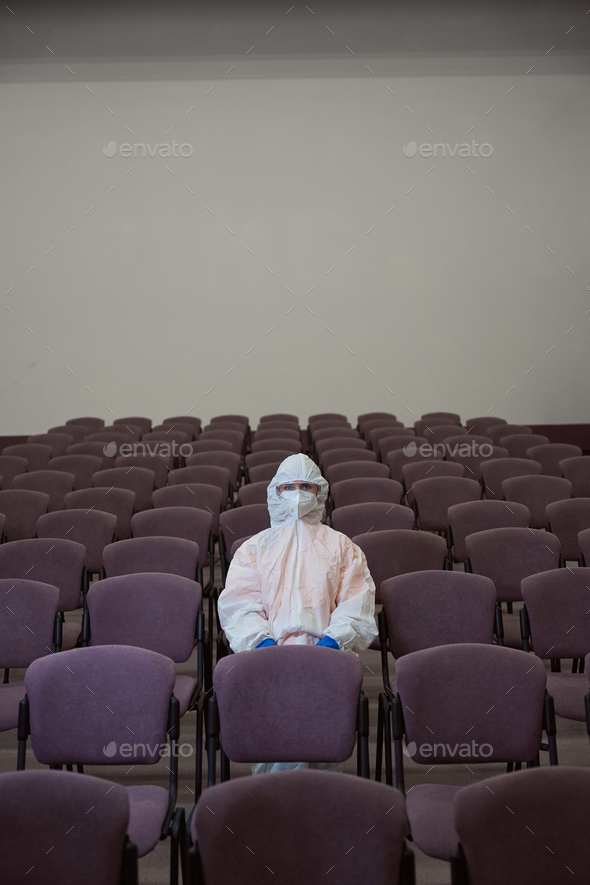 Certified commercial cleaner in protective outfit and mask sitting alone