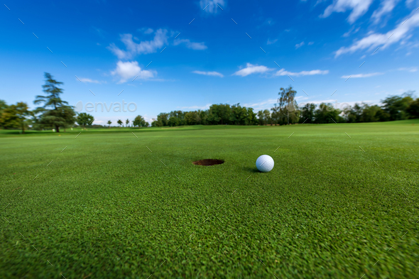 Golf ball on grass near hole - Stock Photo - Images