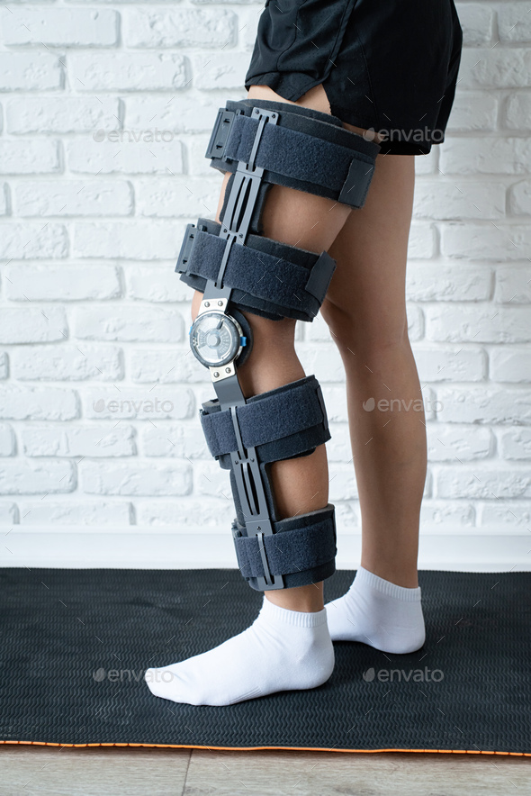 Female wearing knee orthosis or knee support brace after surgery on leg
