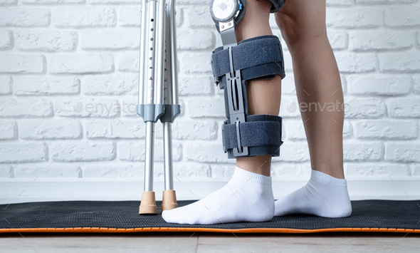 Female wearing knee orthosis or knee support brace after surgery on leg