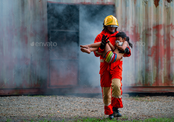 Firefighter help to carry little Asian girl or children out from room cover with smoke after fire.