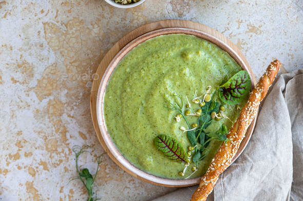 Green vegetable cream soup with micro greens, salad leaves and breadstick