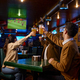 Friends watching football match clinking beer mug rest in sport bar - PhotoDune Item for Sale