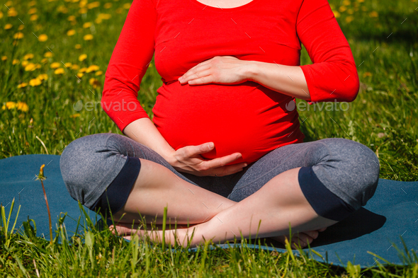 Pregnant woman doing asana Sukhasana outdoors - Stock Photo - Images