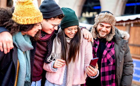 Group of millenial trendy friends walking at city center using mobile phone - Stock Photo - Images