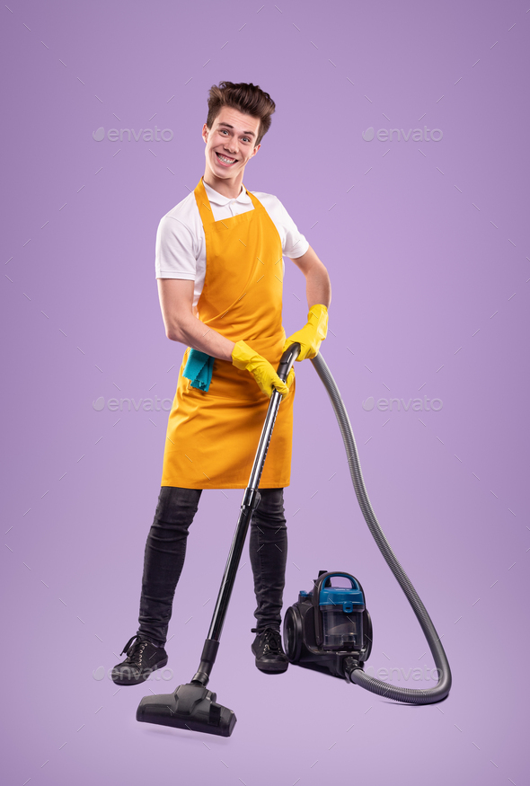 Cheerful housekeeper using vacuum cleaner