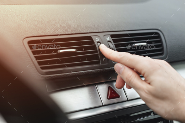 Finger adjusting air outlet deflector of HVAC on dashboard in car