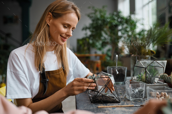 A woman making composition in florarium vase - Stock Photo - Images