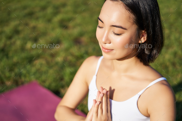 Portrait of young mindful woman, practice yoga, exercising, inhale and exhale on fresh air in park