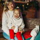 Portrait of a happy little girl sitting on her mother&#39;s lap and drinking hot chocolate on Christmas - PhotoDune Item for Sale