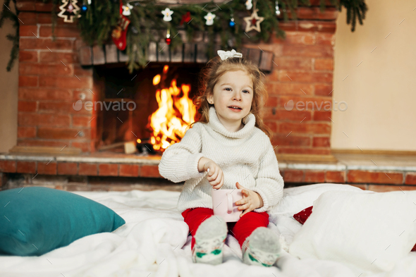 Little girl sitting on Christmas or New Year's eve at home - Stock Photo - Images
