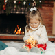 Cute little girl sitting by the fireplace with a Christmas garland.Christmas portrait, cozy style - PhotoDune Item for Sale