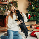 Woman playing with a dog sitting on the floor by the fireplace, on Christmas Eve - PhotoDune Item for Sale