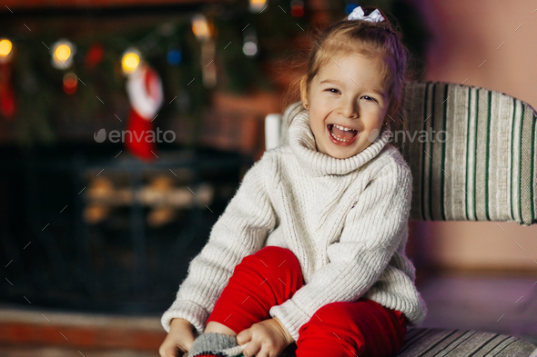 A beautiful little girl is smiling against the background of a Christmas room - Stock Photo - Images