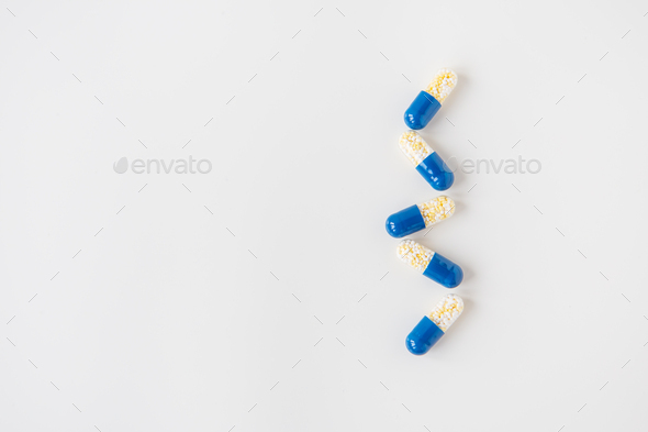 Medical pills-capsules, half blue on a white background, lying in a row. Flat layout, top view