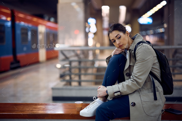 Young sad woman sitting alone in a subway.