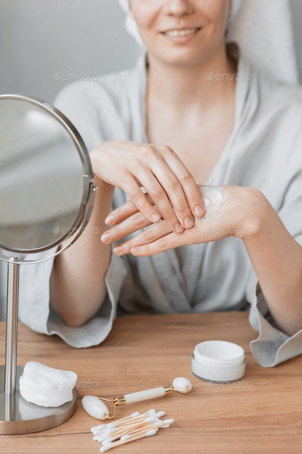 Caucasian woman at home or in the spa applies hand cream or body balm, moisturizing hand