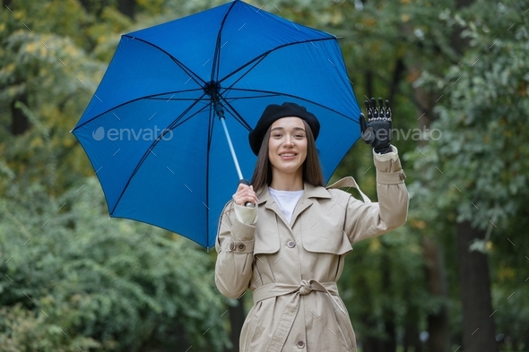  woman with a bionic prosthesis on her arm standing under an umbrella and waving her hand