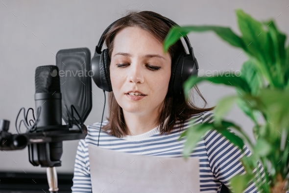 European young and educated woman podcast records audio content in a recording studio