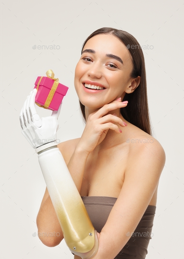 a beautiful European woman with a bionic prosthesis on her arm smiles and holds a gift