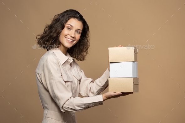 European woman in light clothes holds delivery boxes in her hands and smiles. beauty