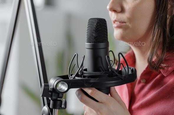 woman recording audio content microphone or a podcast for her blog in a home recording studio