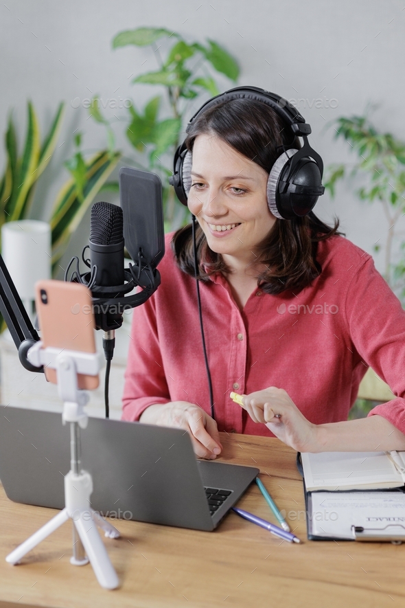 woman recording audio content microphone or a podcast for her blog in a home recording studio.