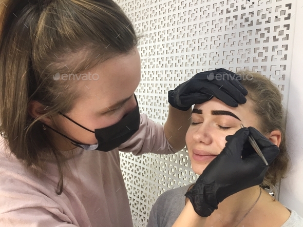 Beautiful young girl gets eyebrow correction and coloring in beauty salon