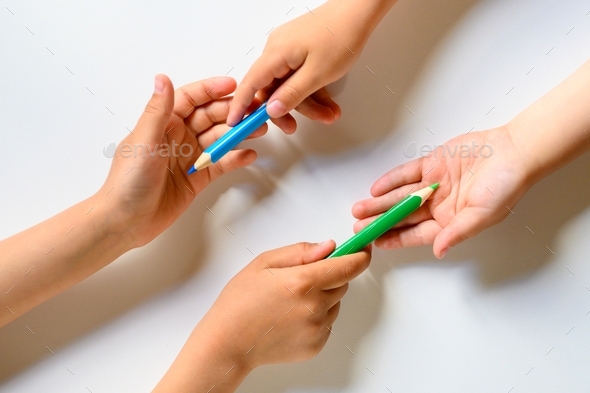 kid's hands share each other colored pencils on a white background