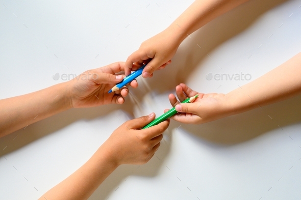 kid's hands share each other colored pencils on a white background