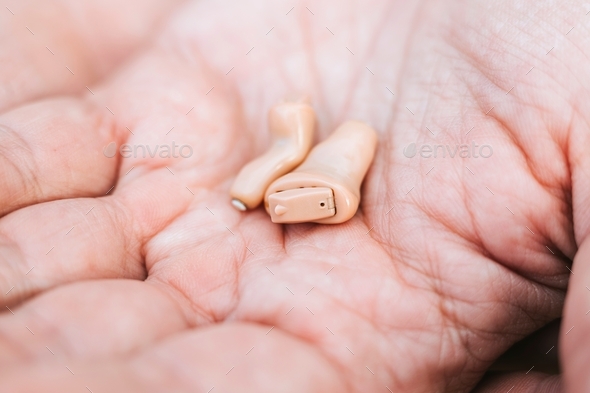 small intra channel hearing aid device in a man\'s hand