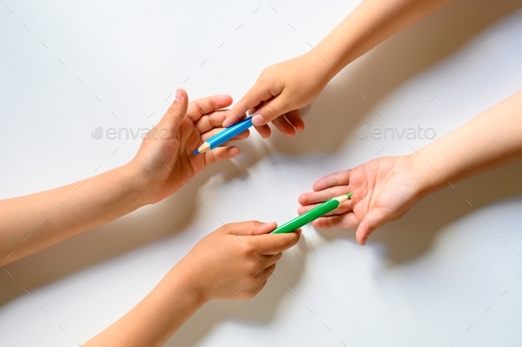 kid\'s hands share each other colored pencils on a white background