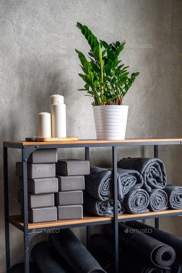 interior of the room for yoga. table rack with accessories - support cubes and rubber mats. plant