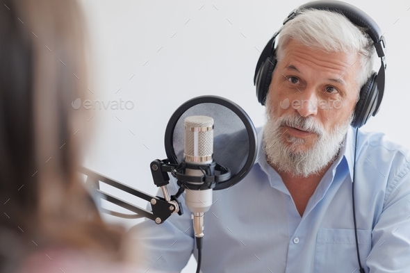 adult man with gray hair and a young woman in a recording studio create audio content